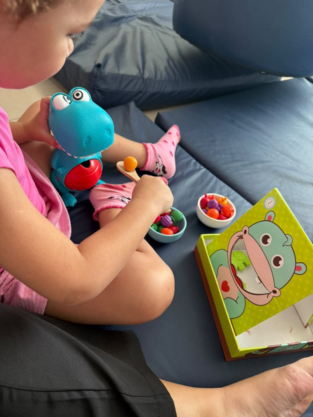Criança brincando com alimentos de brinquedo durante atividade lúdica no consultório